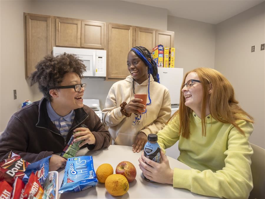 Braxton Gardner, Tamya DeWitt, and Chrislynn Oliver enjoy an after-school snack in the kitchen.